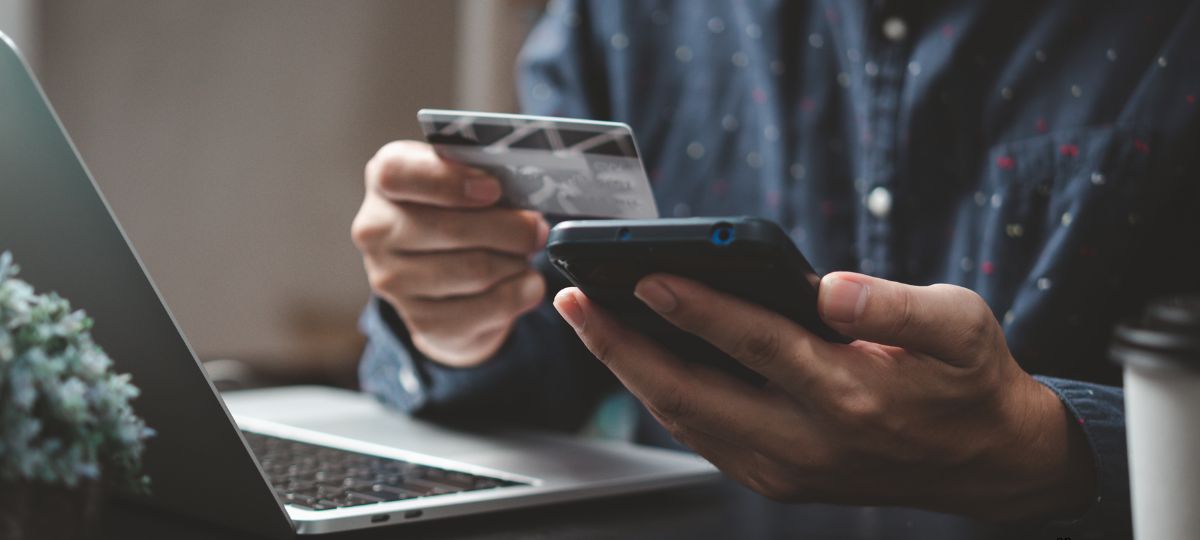 Мужчина держит в руках телефон и банковскую карту