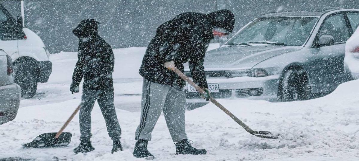 люди убирают снег во время снегопада