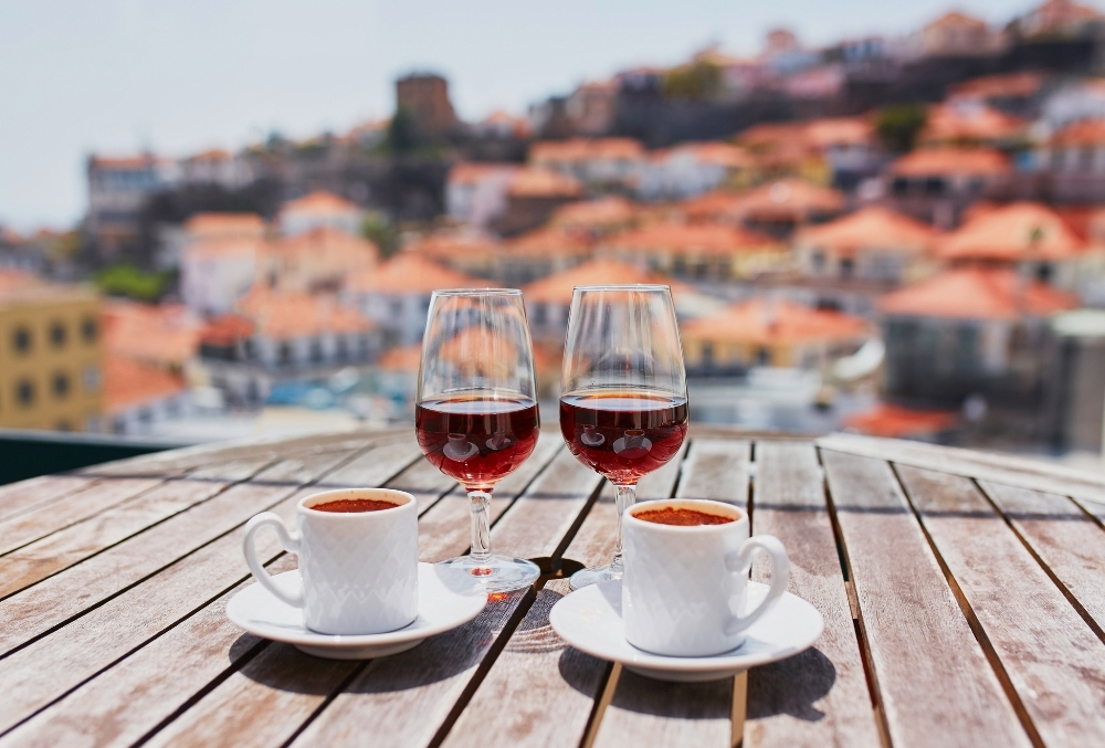 Два бокала вина и две чашки кофе на столе с видом на Лиссабон