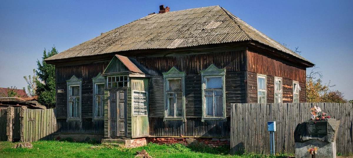 деревянный дом с памятным знаком справа